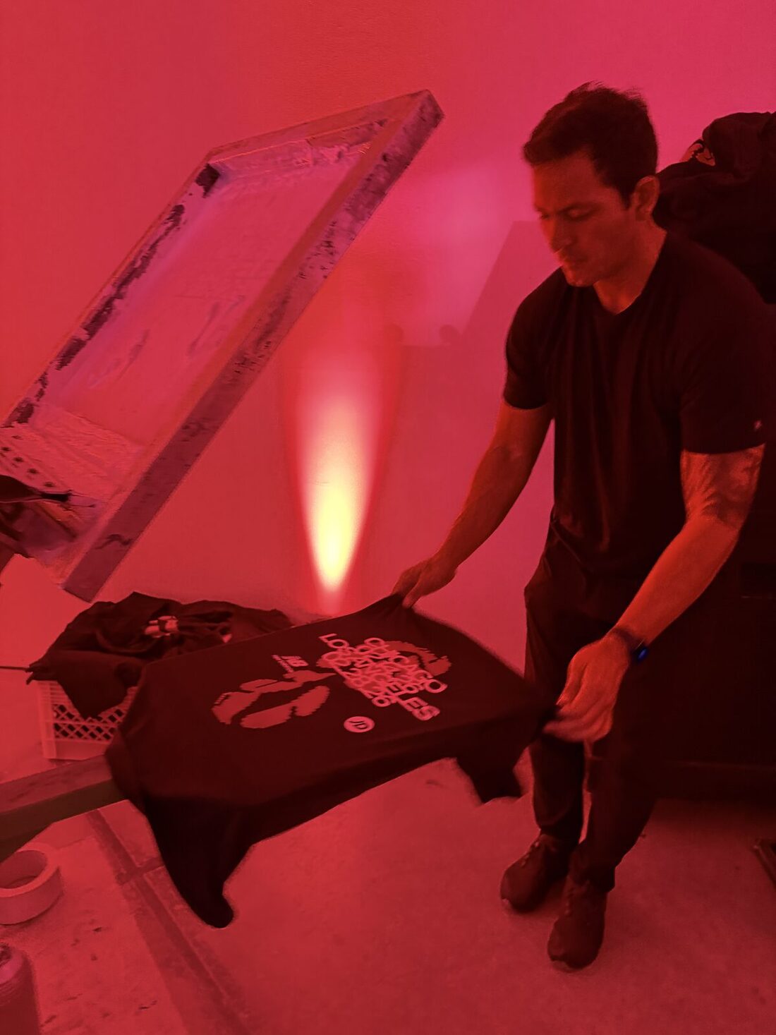 Printer holding up a just-printed black shirt at a live event