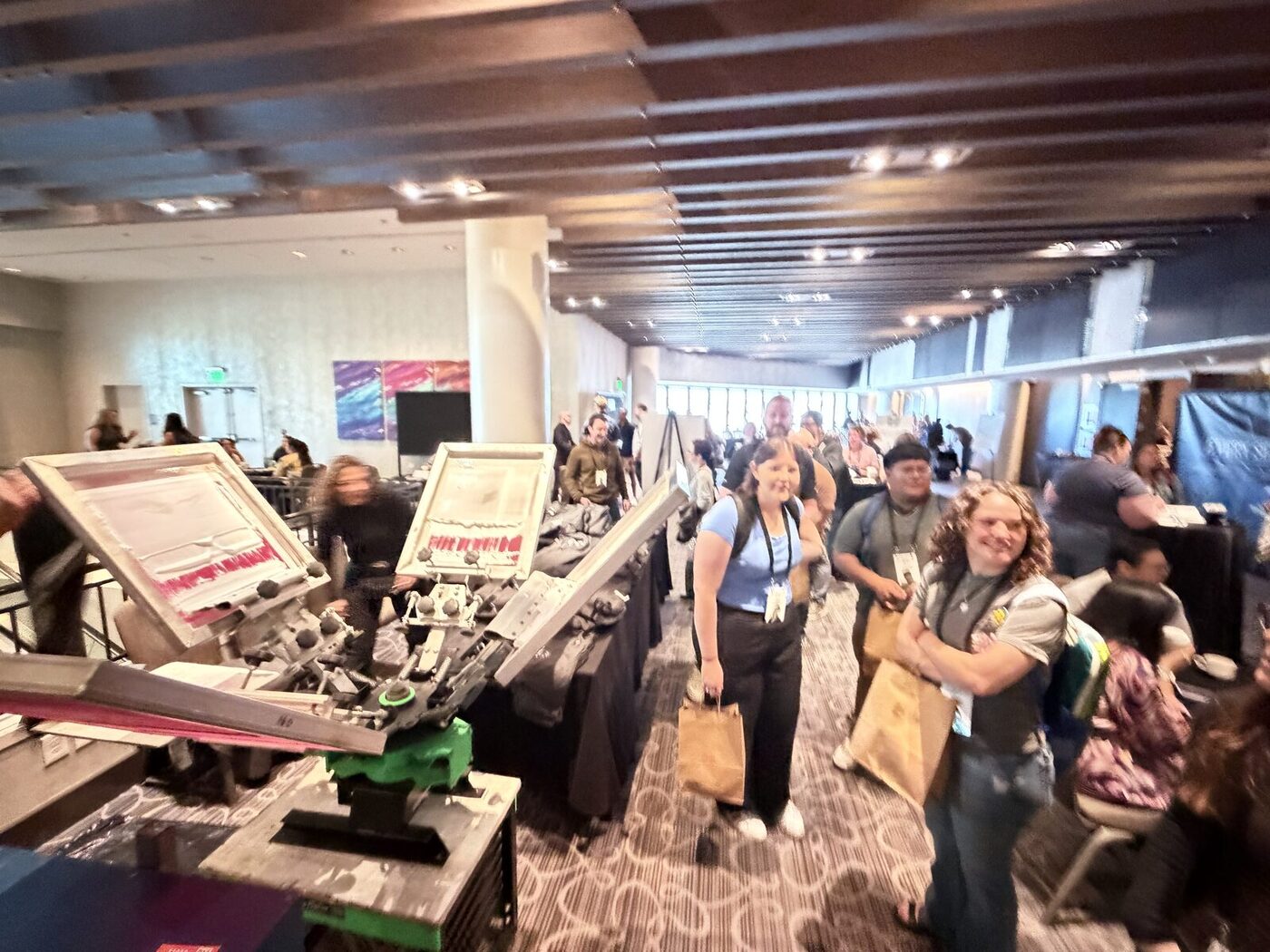 Two screen-printing stations running at an indoor event while guests pick up their printed merch